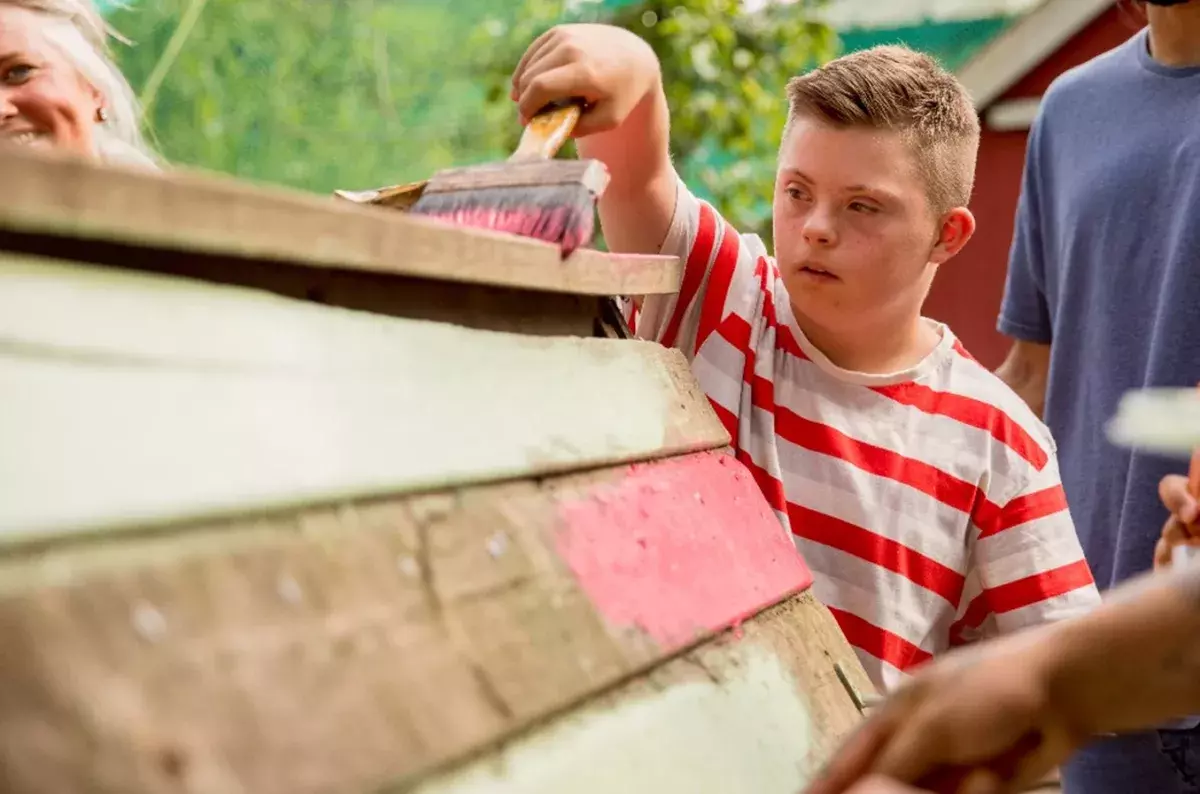 jeune enfant trisomique peignant une cabane